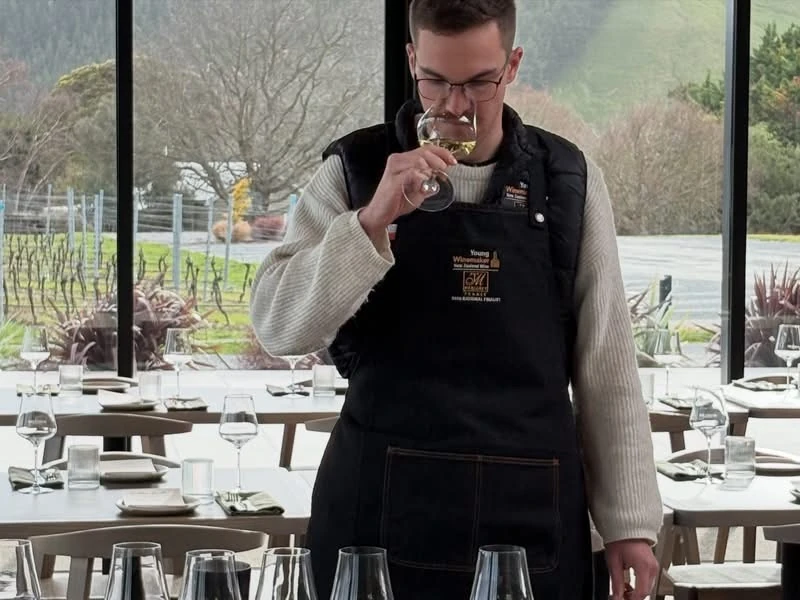 Aaron Coxhead tasting wine in a vineyard restaurant in his Young Winemaker apron